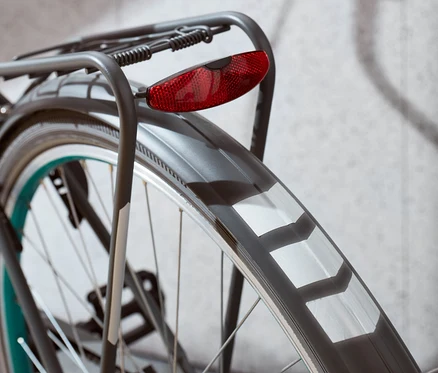 Gros plan de la roue arrière d'un vélo avec un feu rouge et des autocollants réfléchissants.