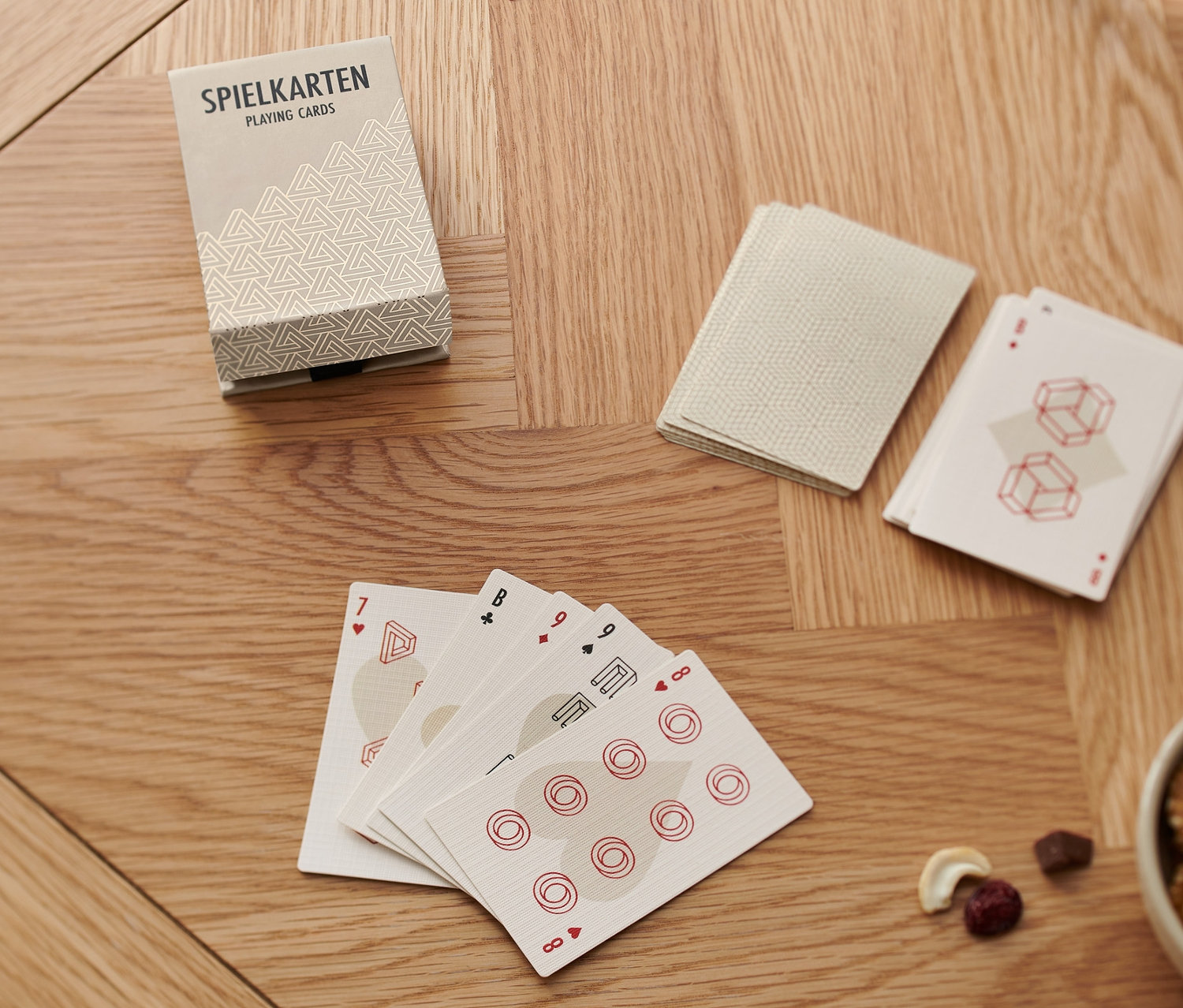 Sur une table en bois sont posés un jeu de cartes « Skat », un verre d'eau et un bol de noix.