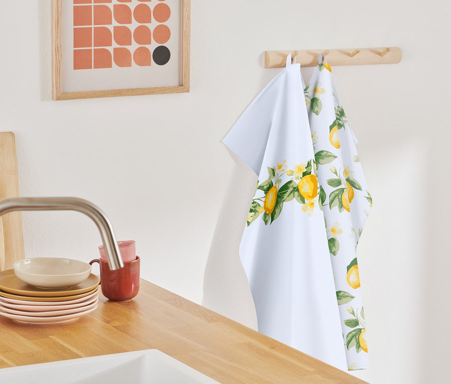 Deux linges de cuisine à motif citron sont suspendus à une barre en bois.
