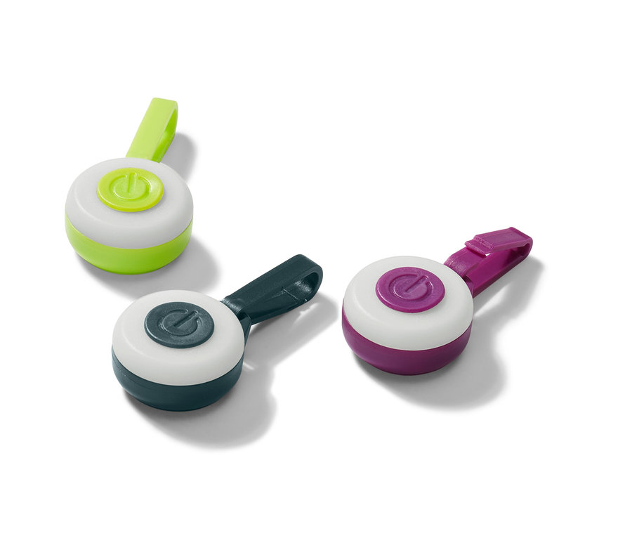 Trois pendentifs LED en vert, bleu foncé et violet reposent sur une surface blanche.