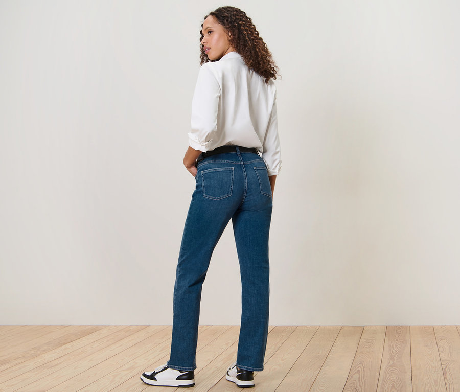 Une femme regardant par-dessus son épaule pose en jean droit – Fit « Kira », bleu moyen.