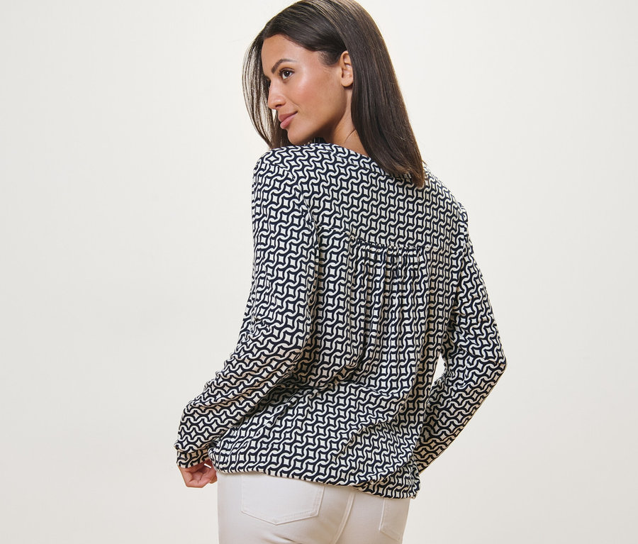 Femme regardant par-dessus son épaule portant une blouse imprimée bleu marine.
