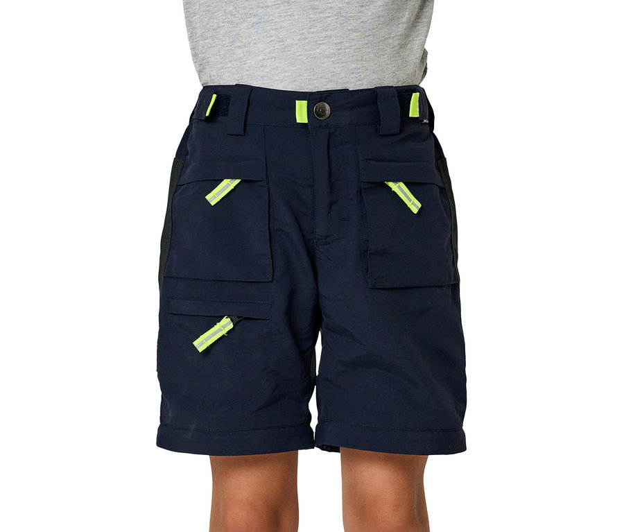 Un enfant porte un short marine du pantalon zip-off JAKO-O, avec des détails jaune fluo sur les poches et la ceinture.
