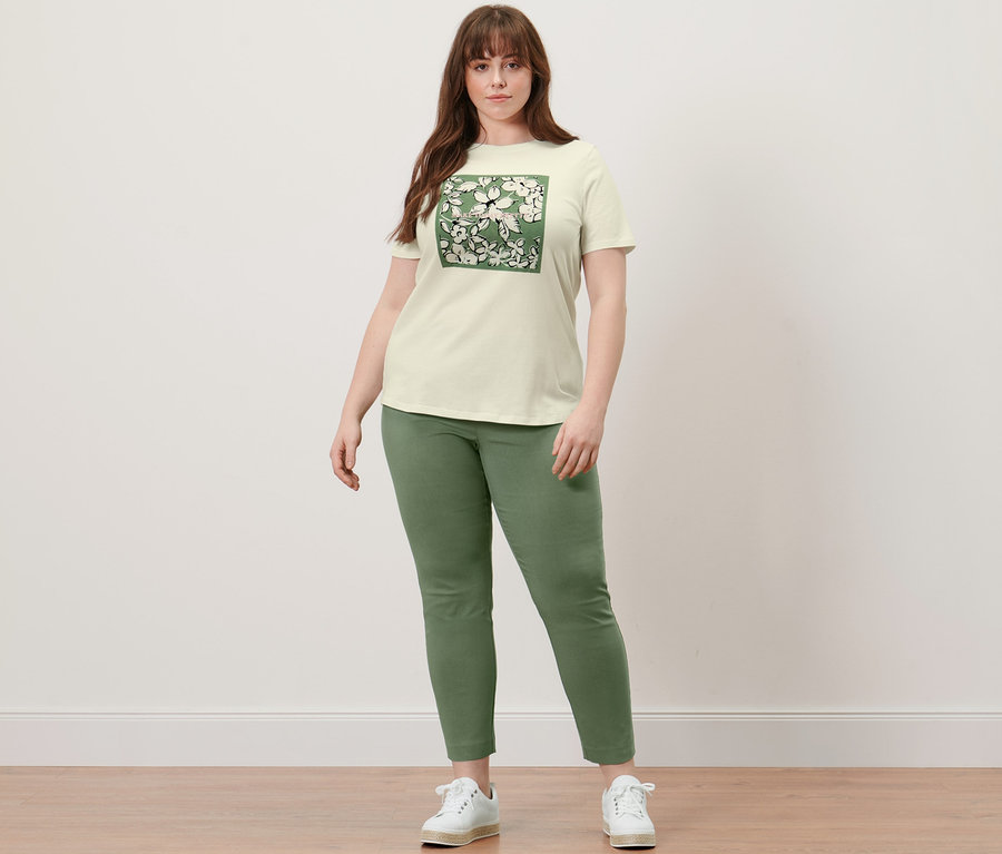 Femme debout portant un t-shirt à imprimé et un pantalon stretch.