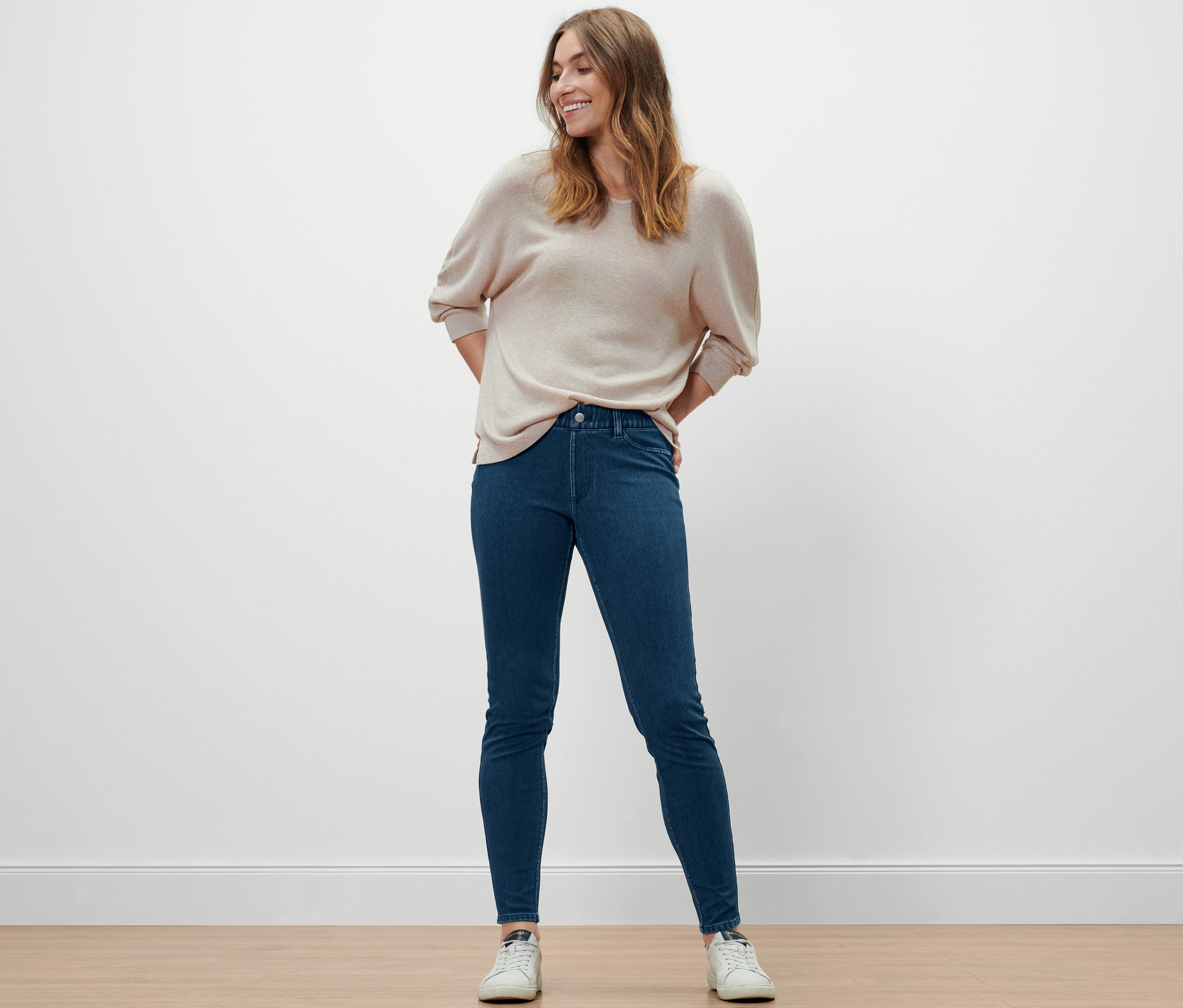 Femme posant en jegging, pull et baskets.