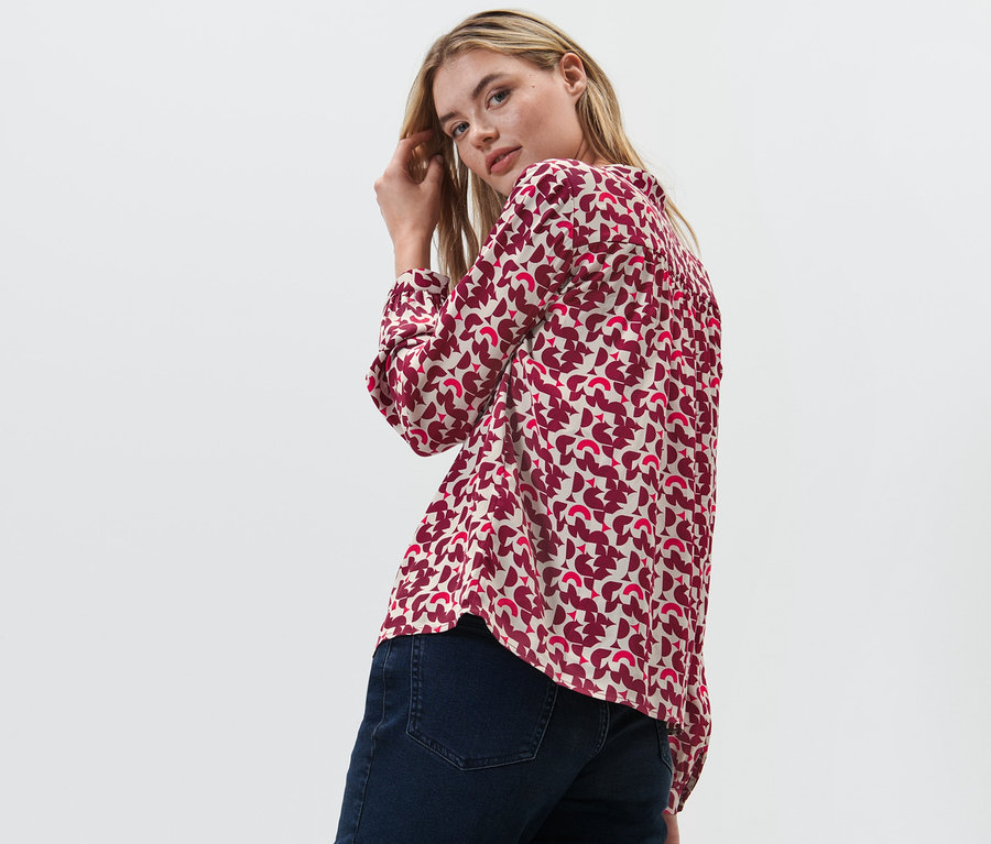 Femme regardant par-dessus son épaule et posant en chemisier imprimé.