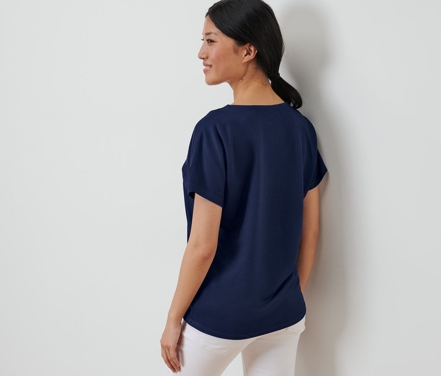 Femme posant dans une blouse structurée bleu foncé.