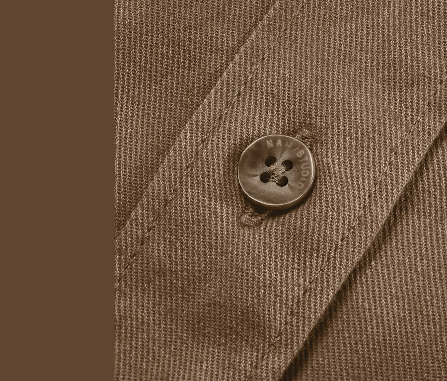 Gros plan sur une blouse NAH/STUDIO en coton durable couleur noisette, avec un bouton visible.