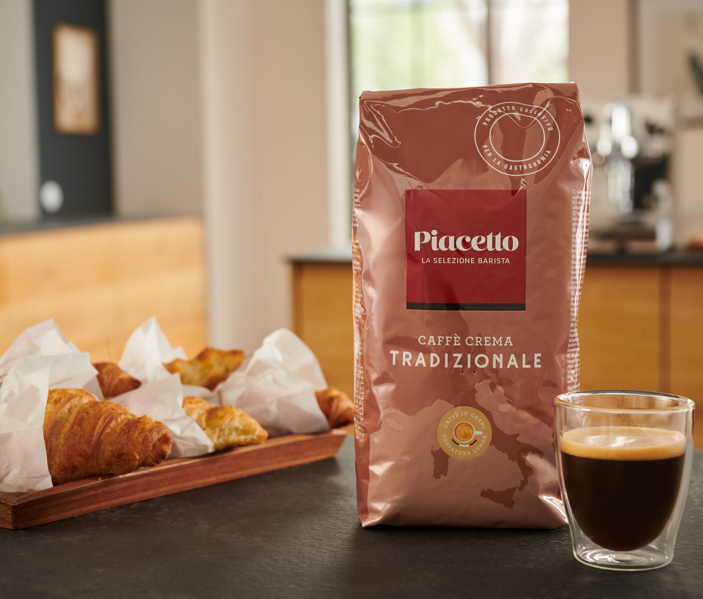 Un paquet de Piacetto Caffè Crema Tradizionale, du café et des croissants sur une table.