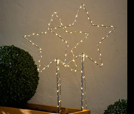 Deux grands piquets de terre à LED « étoile » dans un bac à fleurs en bois.