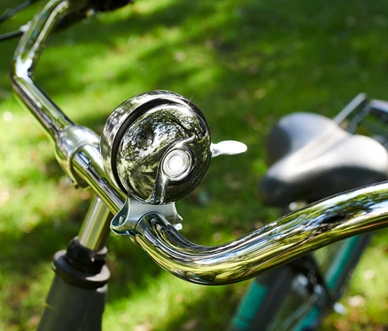 Gros plan d'un guidon de vélo chromé avec une sonnette de vélo.