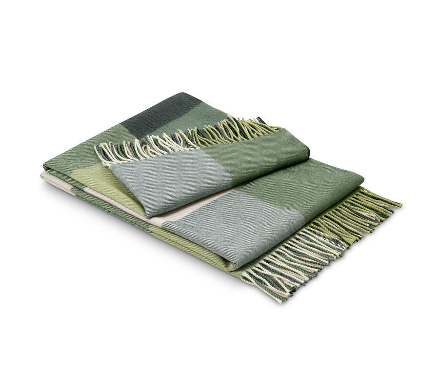 Un plaid vert à carreaux plié avec des franges.