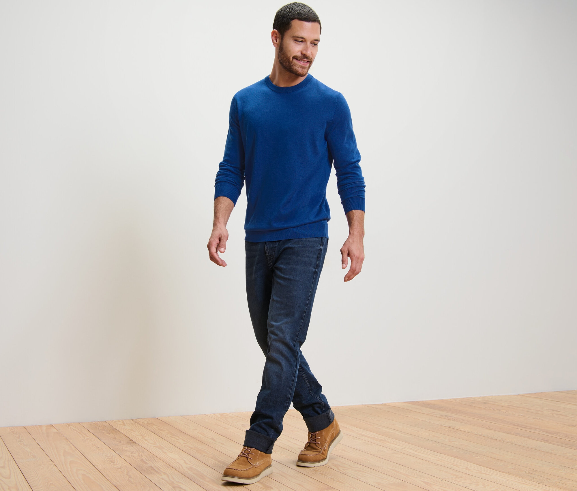 Un homme marche et porte un pull en mérinos bleu.