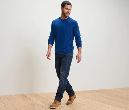 Un homme marche et porte un pull en mérinos bleu.