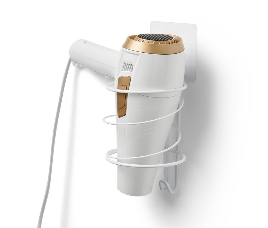 Un support à sèche-cheveux blanc est fixé sur un mur blanc et maintient un sèche-cheveux blanc.