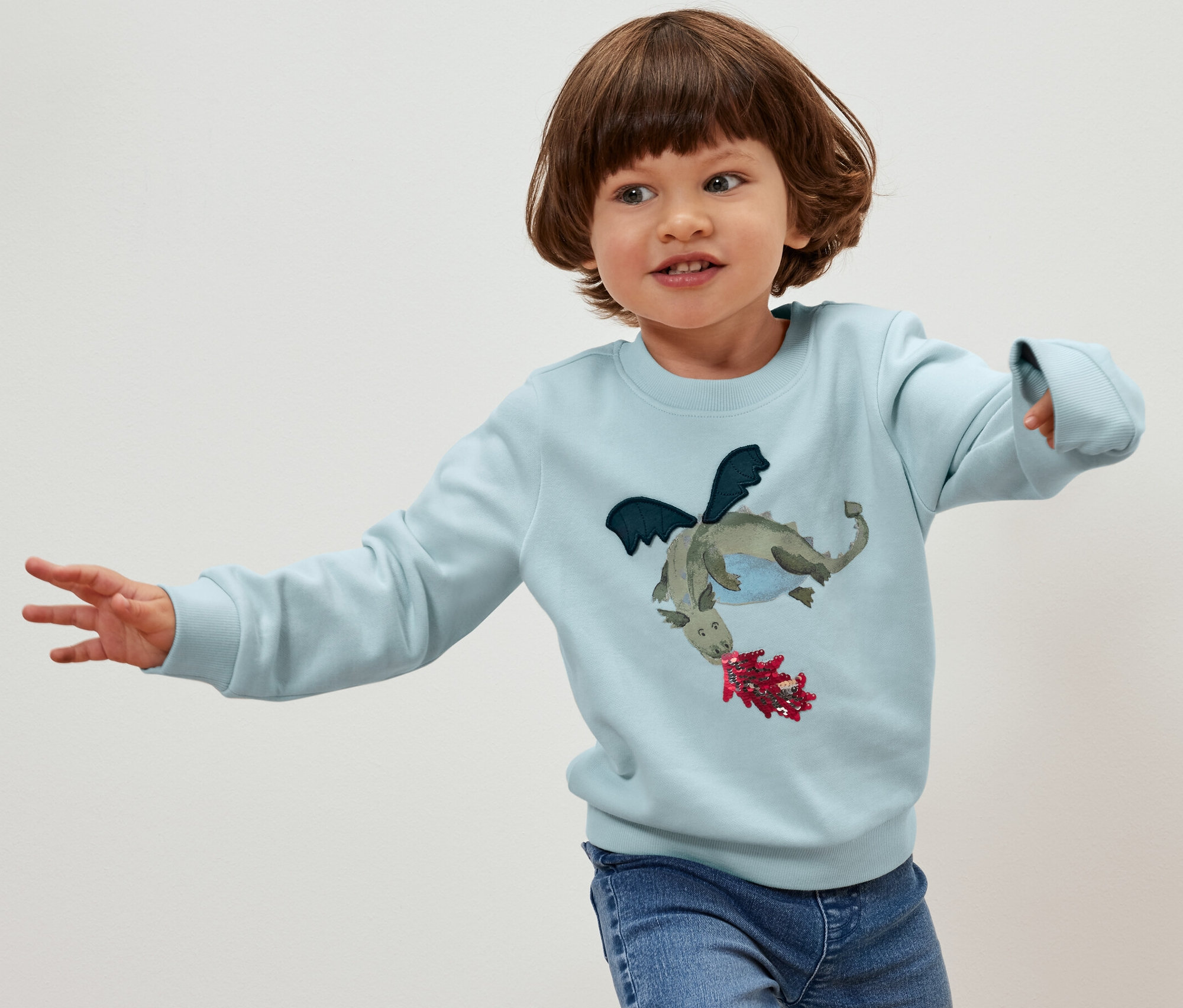 Un enfant pose dans un sweat-shirt pour enfant avec intérieur gratté, dragon.
