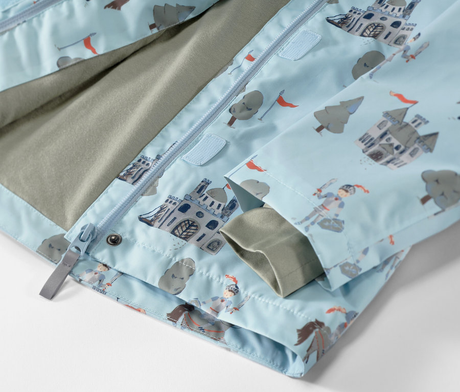 Détail d'une veste de pluie pour enfant avec un motif de chevalier.