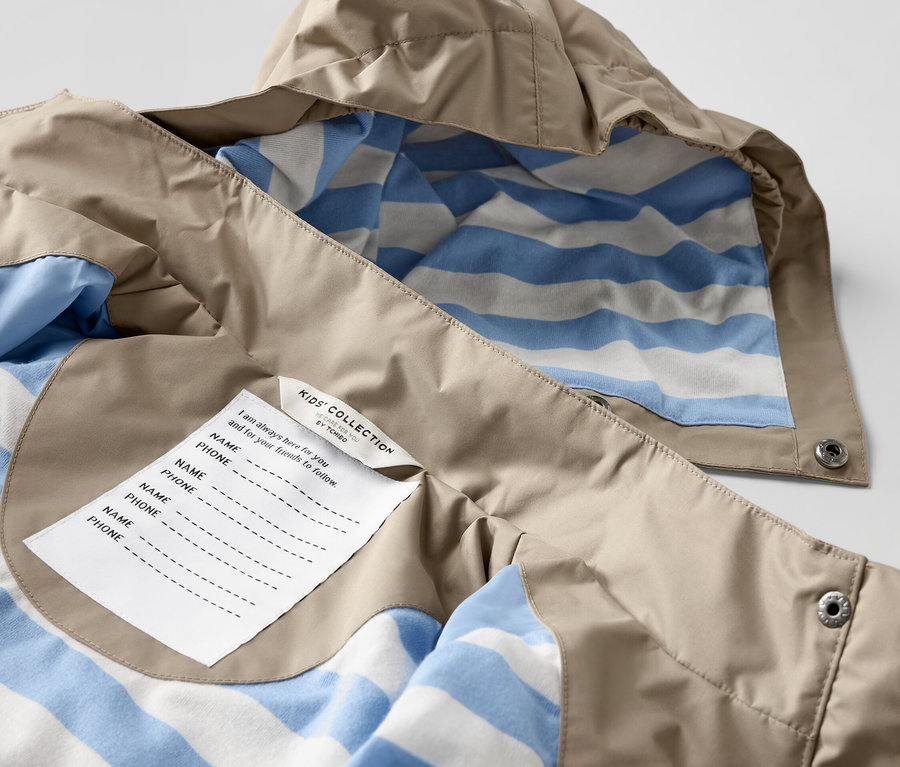 Gros plan sur une veste de pluie marron pour enfant avec une doublure rayée bleu et blanc.