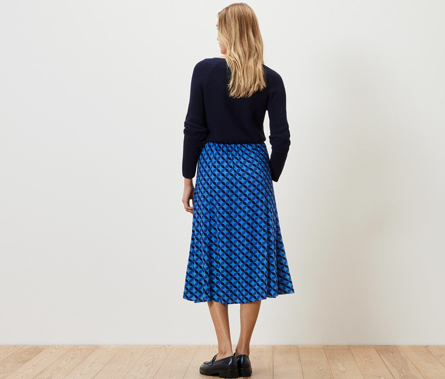 Une femme, vue de dos, porte une jupe midi imprimée bleu foncé.