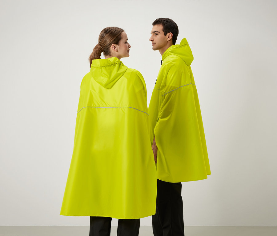 Deux personnes se tiennent côte à côte portant des ponchos de pluie jaunes à capuche.