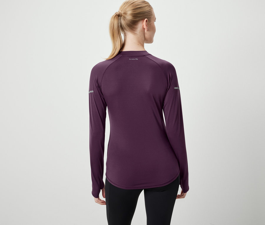 Une femme, dos à la caméra, porte un t-shirt à manches longues violet et un legging noir.