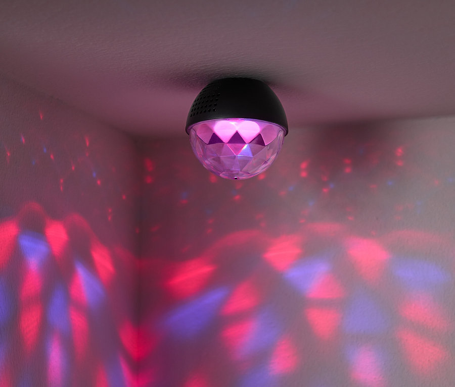 Une boule disco est fixée au plafond et projette des lumières rouges et bleues sur les murs de la pièce.