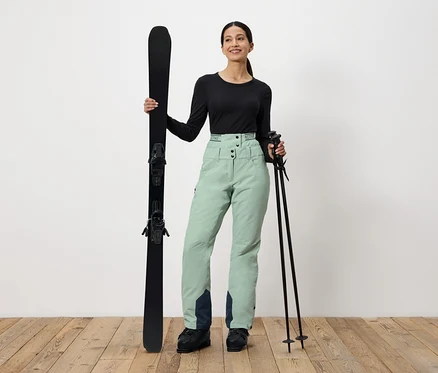 Femme tenant des skis et des bâtons de ski.