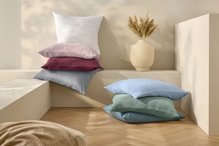 Coussins empilés et parure de lit en lin blanche de taille standard.