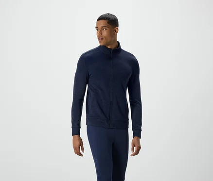 Homme en veste zippée bleu marine et pantalon regardant vers la gauche.