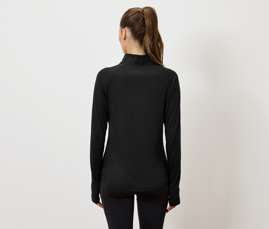 Vue de dos d'une femme avec une queue de cheval portant un haut de sport noir à manches longues et un legging noir.