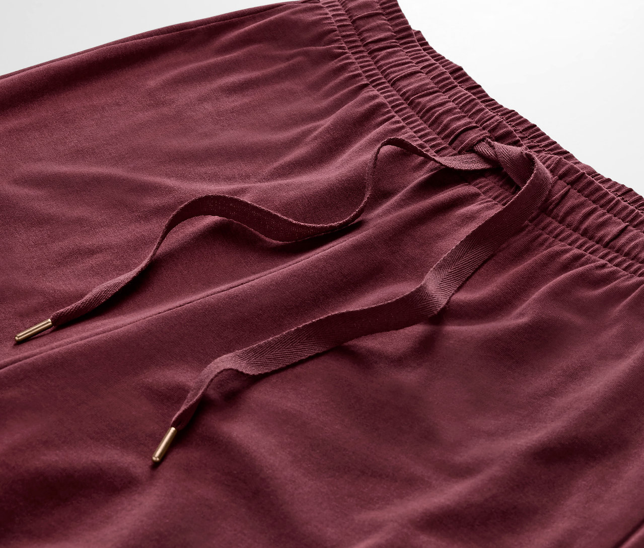 Détail d'un pantalon de survêtement bordeaux avec cordon de serrage.
