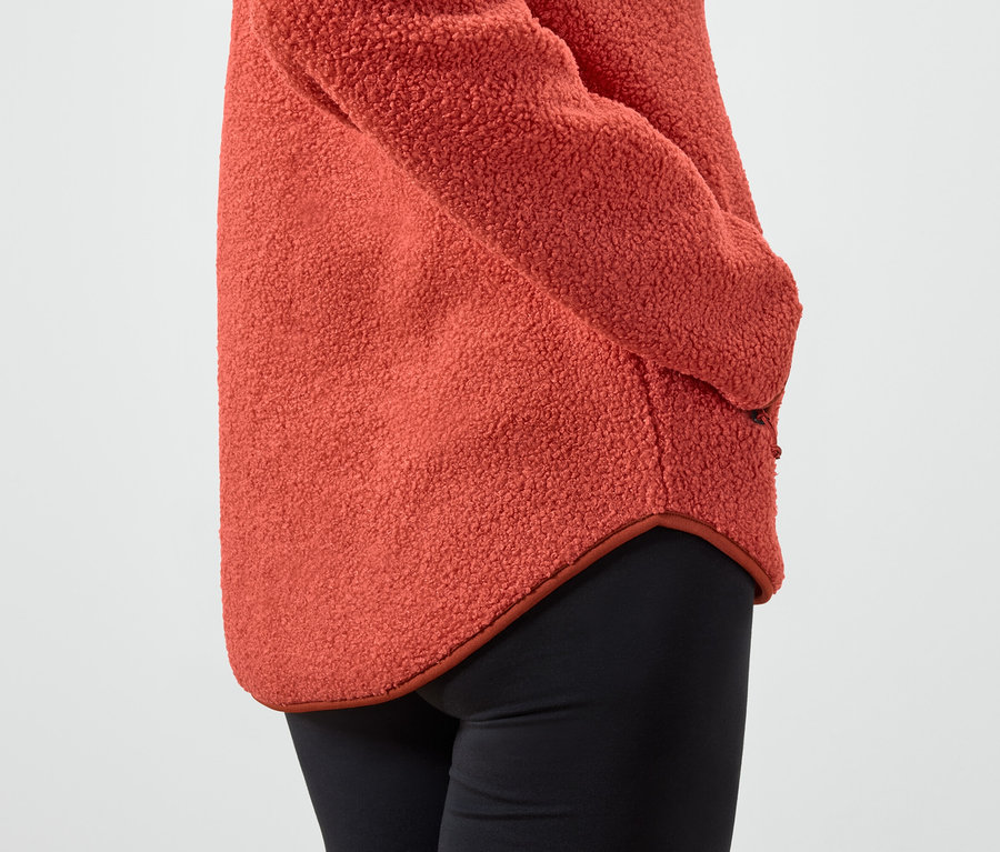 Détail d'un pull en polaire orange pour femme et d'un legging noir.