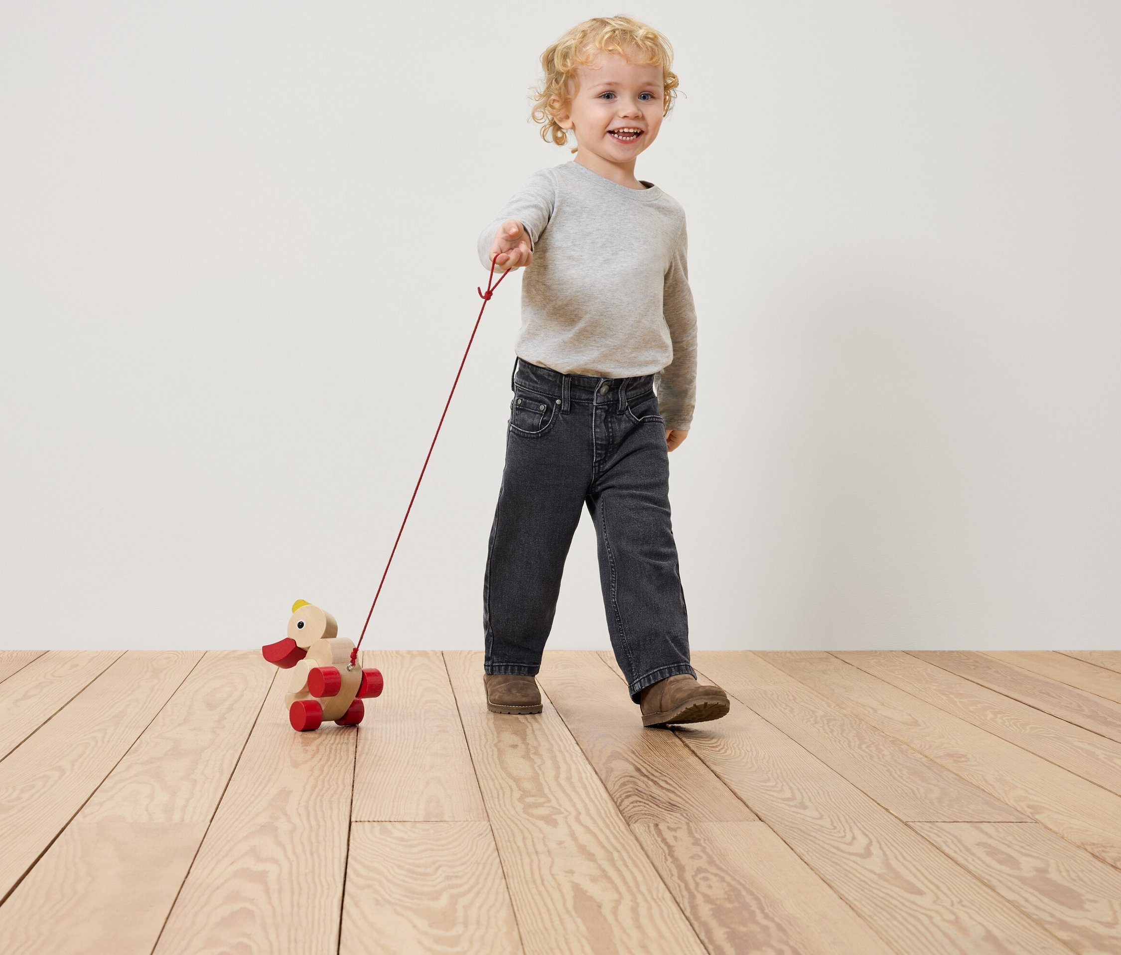 Un garçon tire un canard en bois avec une ficelle.