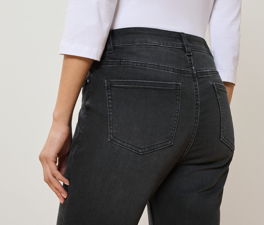 Vue arrière d'une femme portant un jean noir et un t-shirt blanc.