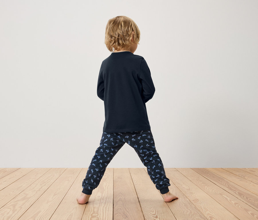 Garçon vu de dos portant un pyjama bleu marine à manches longues et un pantalon à motifs.