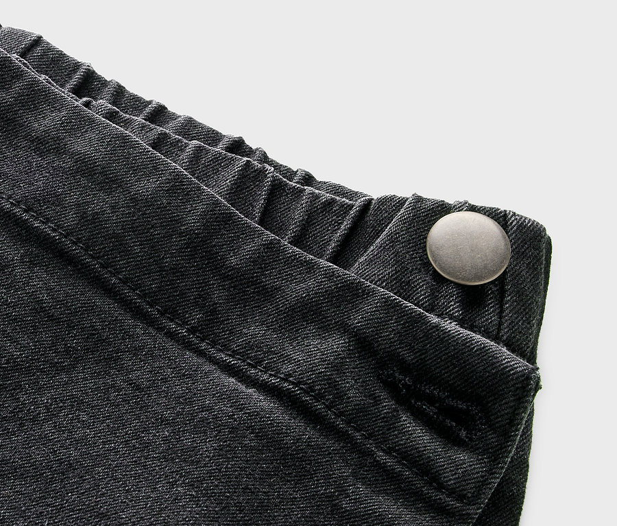 Détail d'une jupe-pantalon pour enfant avec aspect jeans et bouton.