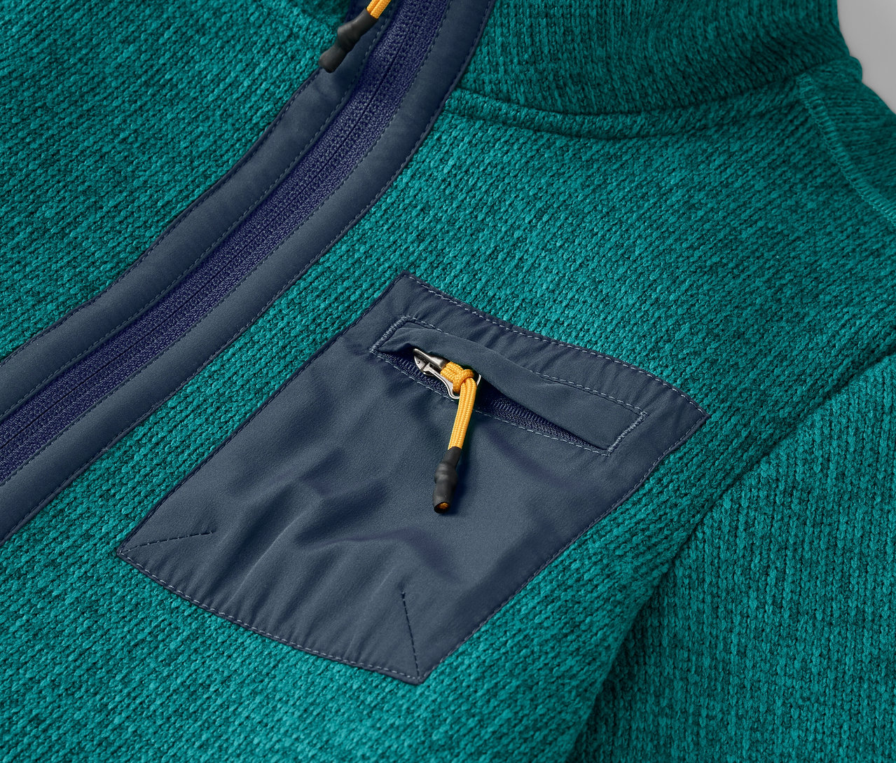 Gros plan sur un pull en polaire bleu-vert avec une poche de poitrine zippée.