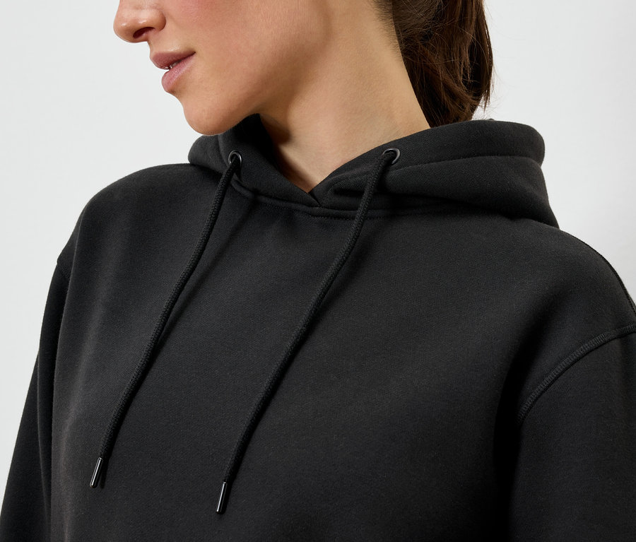 Une femme porte un sweat à capuche noir.