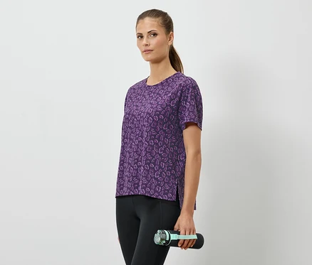 Femme tenant une bouteille d'eau, portant un t-shirt violet et un legging noir.