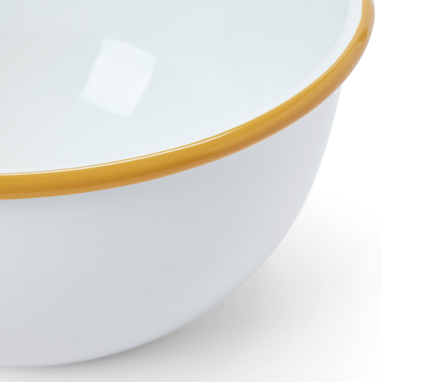 Gros plan sur un plat de service en émail blanc avec un bord marron.