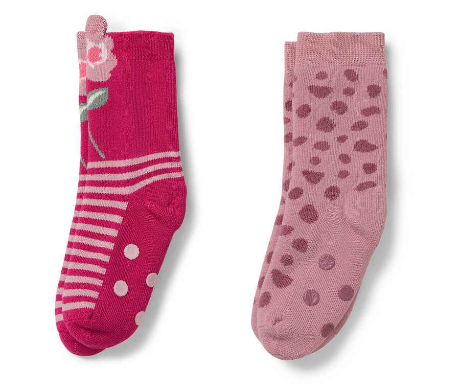 Deux paires de chaussettes. Une paire rose avec un motif floral, l'autre rose clair avec des pois.