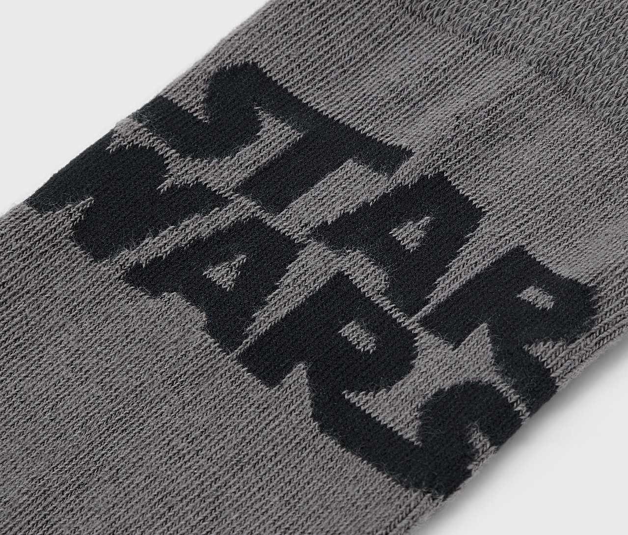 Gros plan d'une chaussette grise avec le lettrage noir STAR WARS.