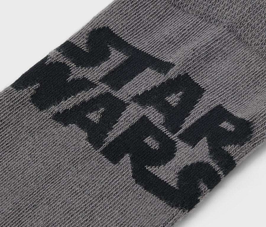 Gros plan d'une chaussette grise avec le lettrage noir STAR WARS.