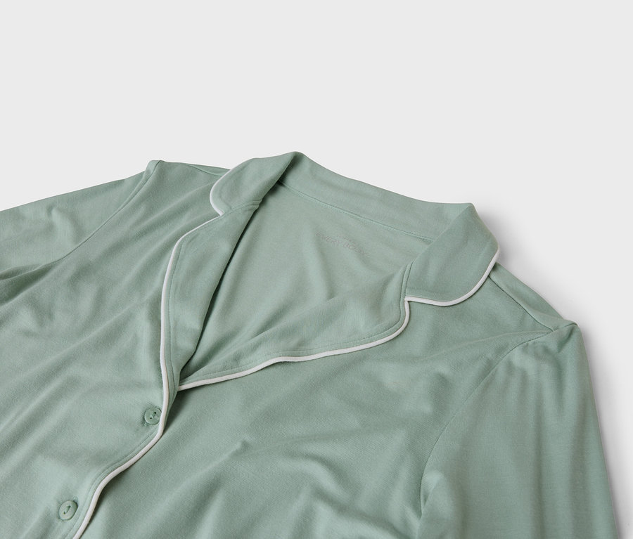 Gros plan sur un haut de pyjama vert clair avec une bordure blanche.