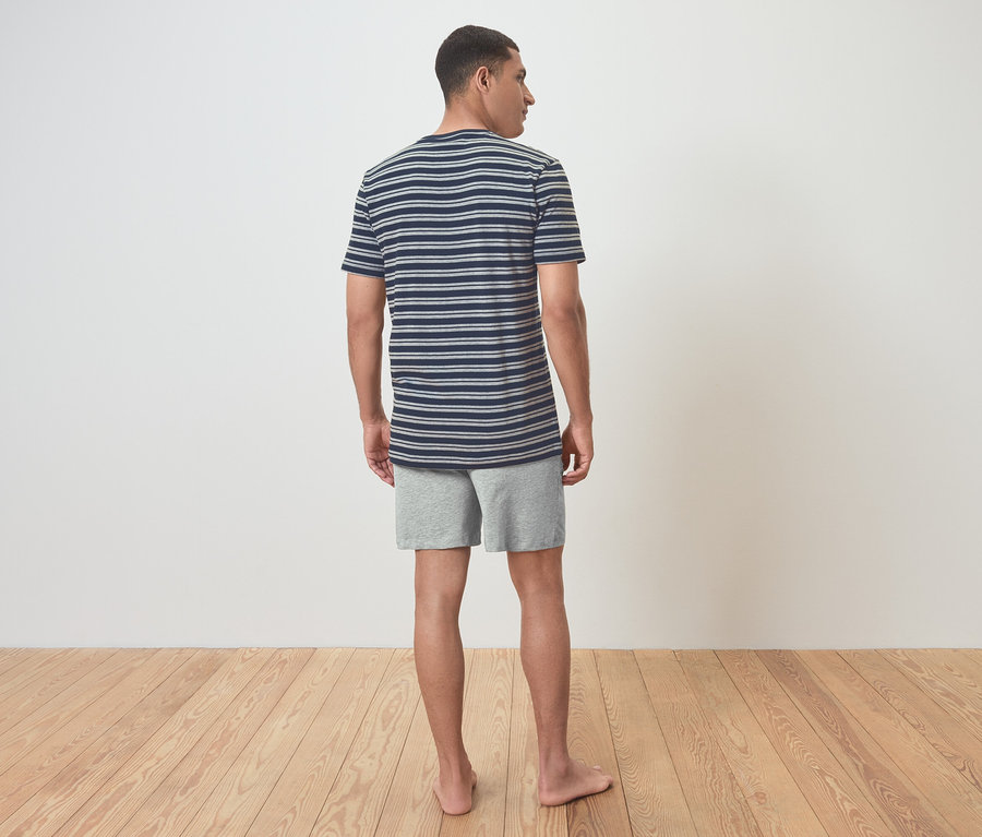 Un homme en t-shirt rayé et short, vu de dos.