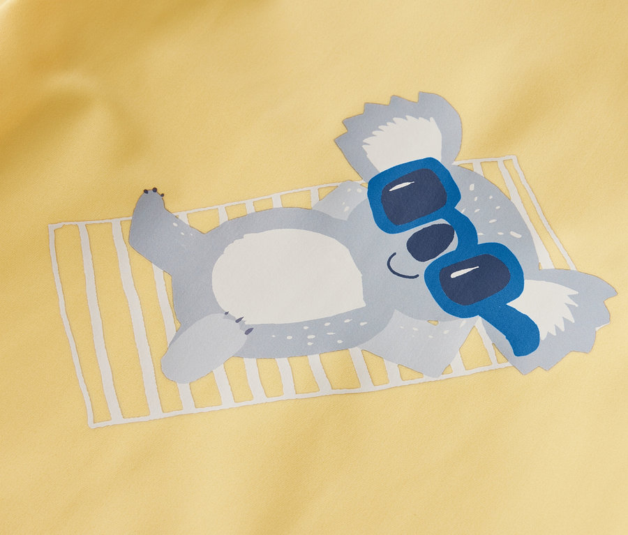 T-shirt jaune pour enfant avec protection UV 80, un koala allongé portant des lunettes de soleil bleues.