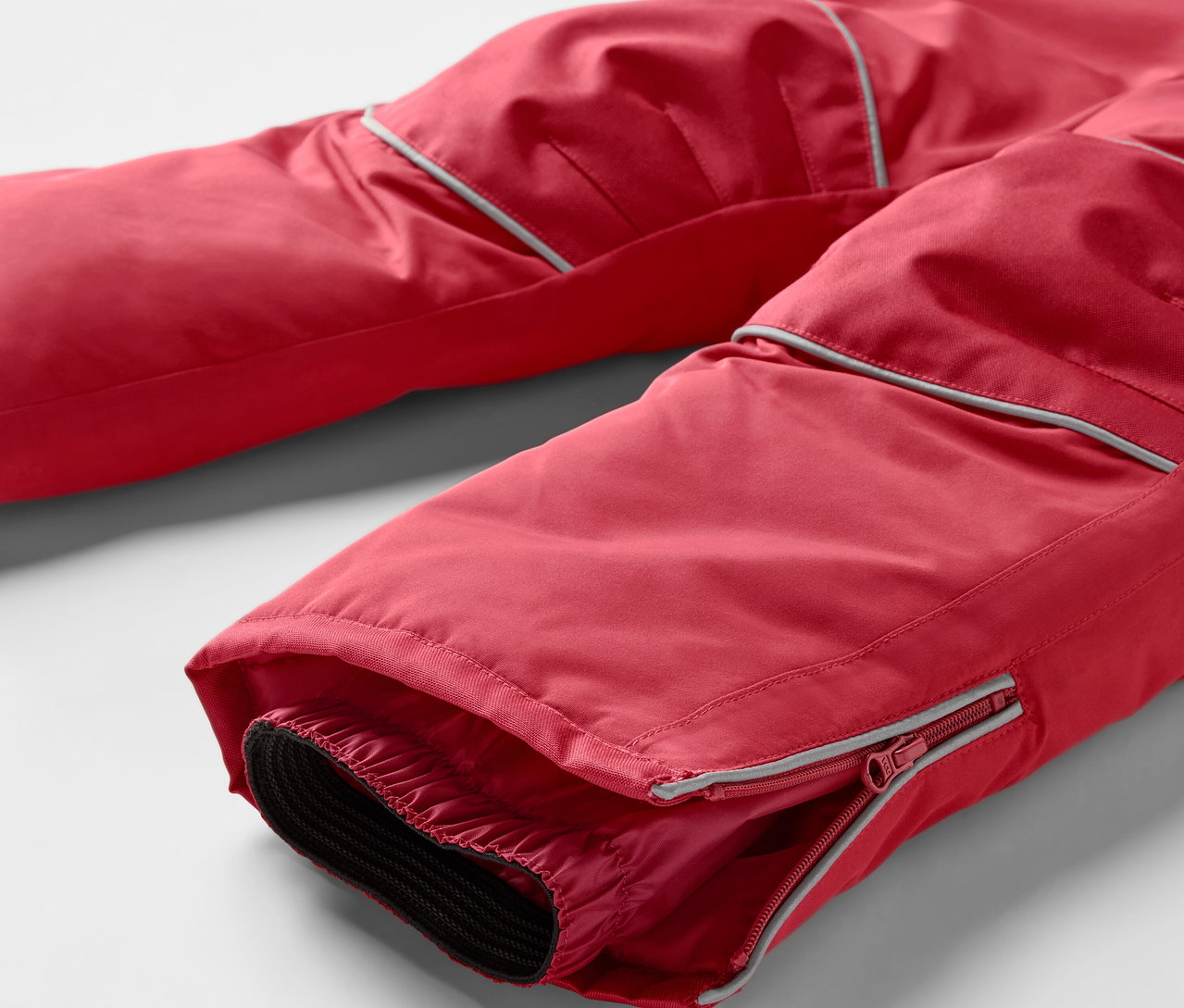 Détail d'un pantalon de ski rouge avec fermeture éclair sur la jambe.
