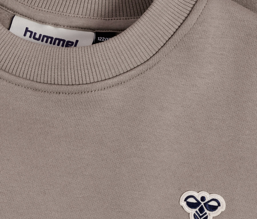 Gros plan d'un sweat-shirt Hummel marron clair avec un col côtelé et le logo Hummel.