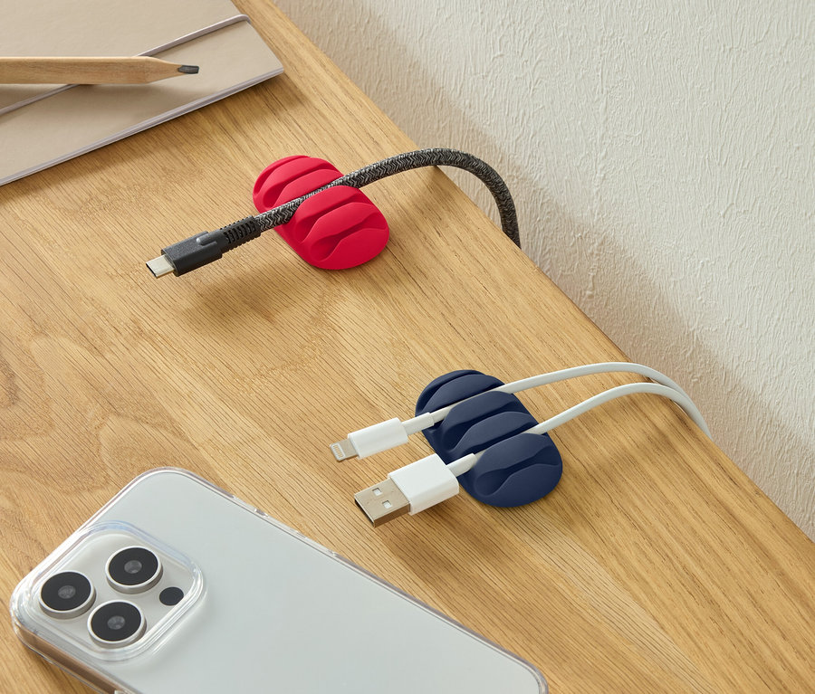 Un câble USB-C dans un serre-câble rouge, deux câbles USB dans un serre-câble bleu et un smartphone sur un bureau.