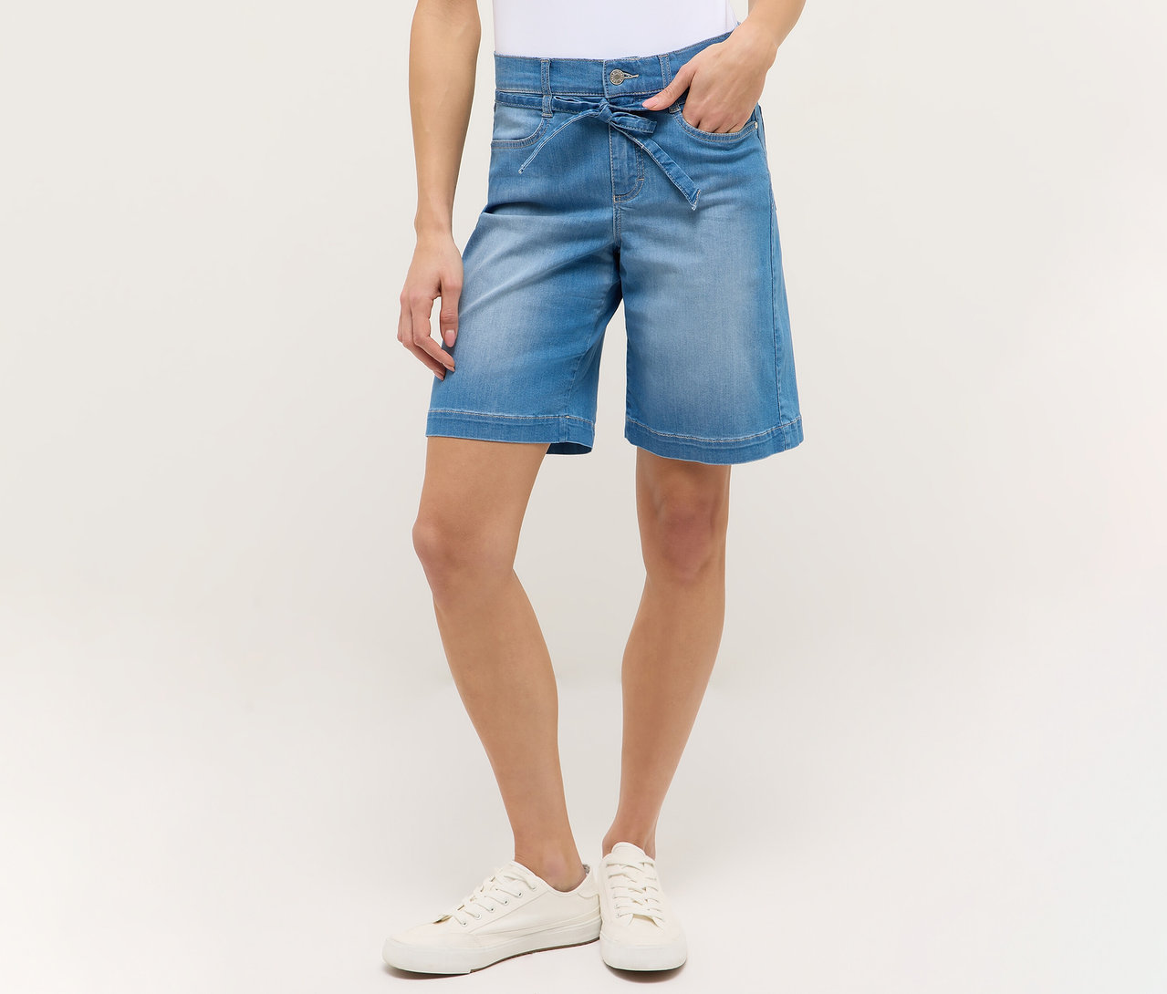 Femme portant un short Angels Denim «
Lia City
» bleu clair et des chaussures blanches, main dans la poche.